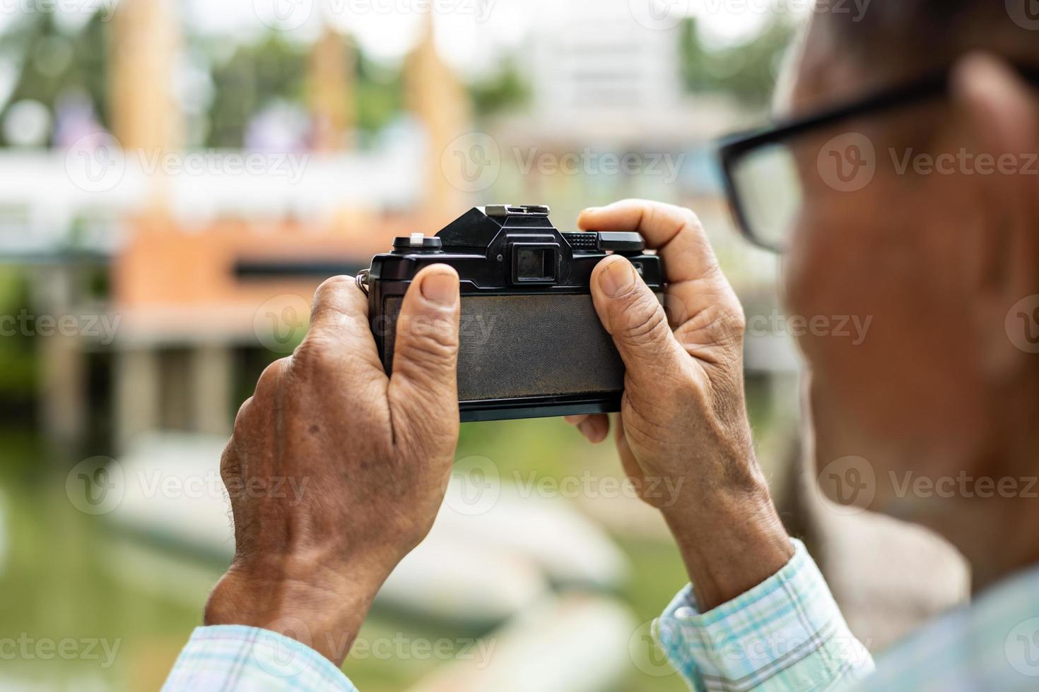 View from the back of an elderly man taking pictures with an old film camera. photo