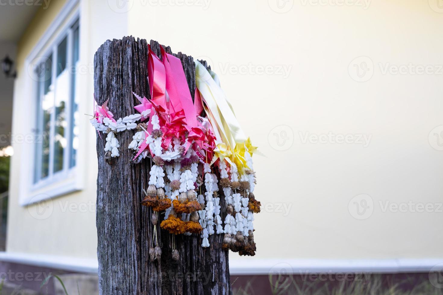 Close-up view of dried flowers, an old garland for worship hanging on a decaying wooden pole. photo