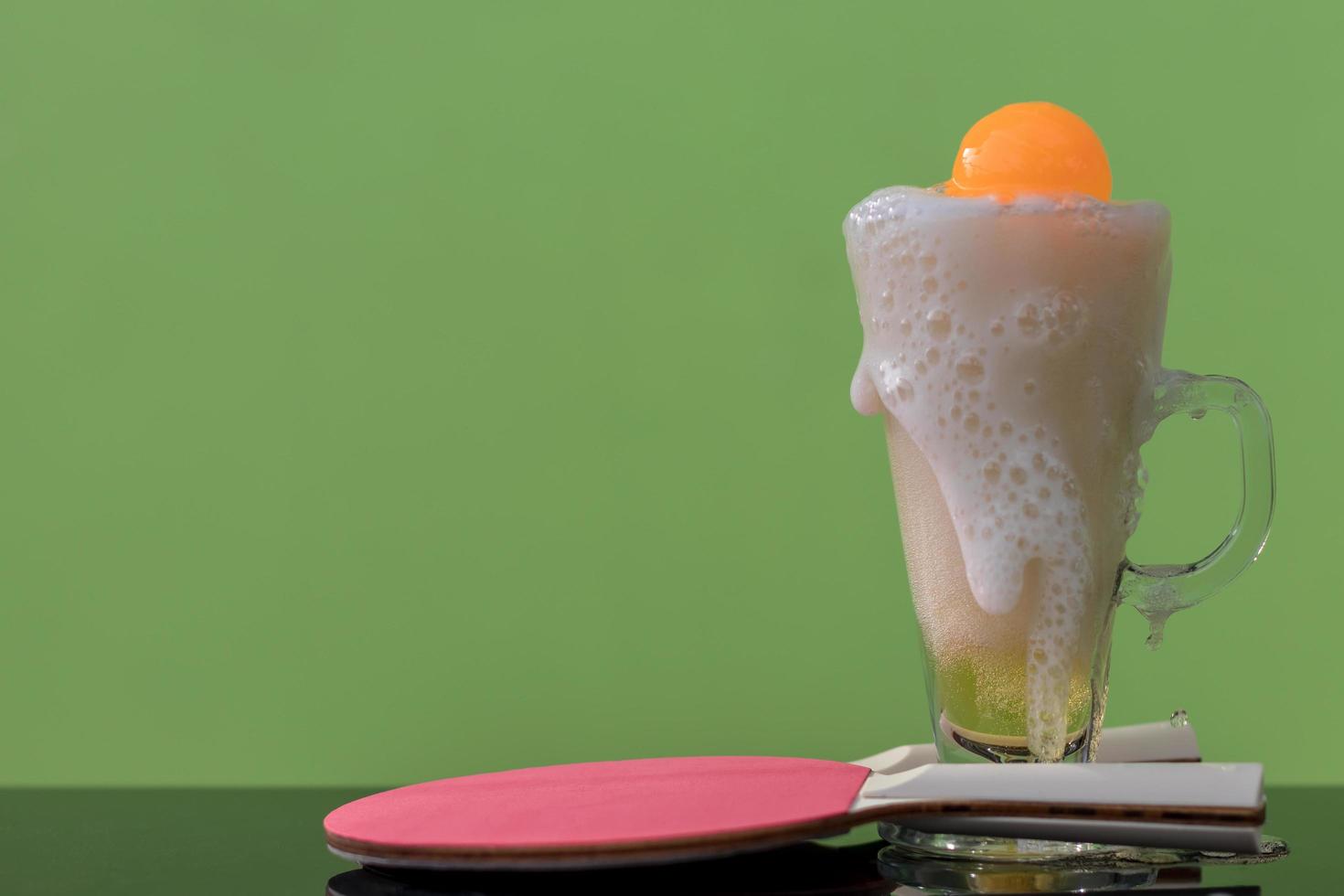 Bubbles of beer in a glass with a ping pong ball. photo