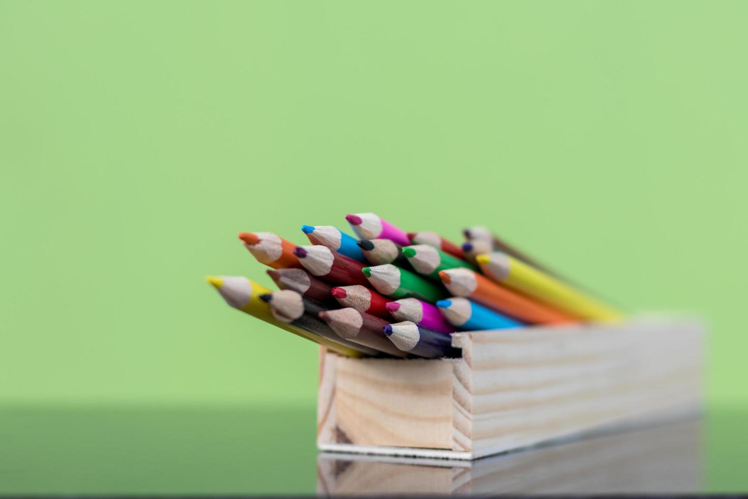 Crayons in a wooden box with green walls. photo