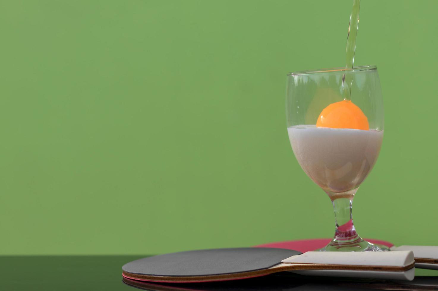 Bubbles of beer in a glass with a ping pong ball. photo