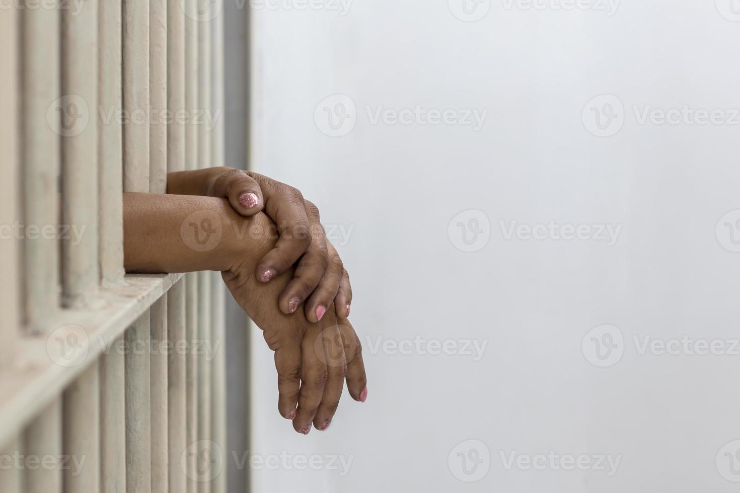 Female prisoner hand on white iron cell bars. photo