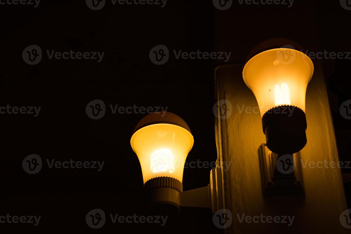 Yellow light bulb with pole in dark room. photo