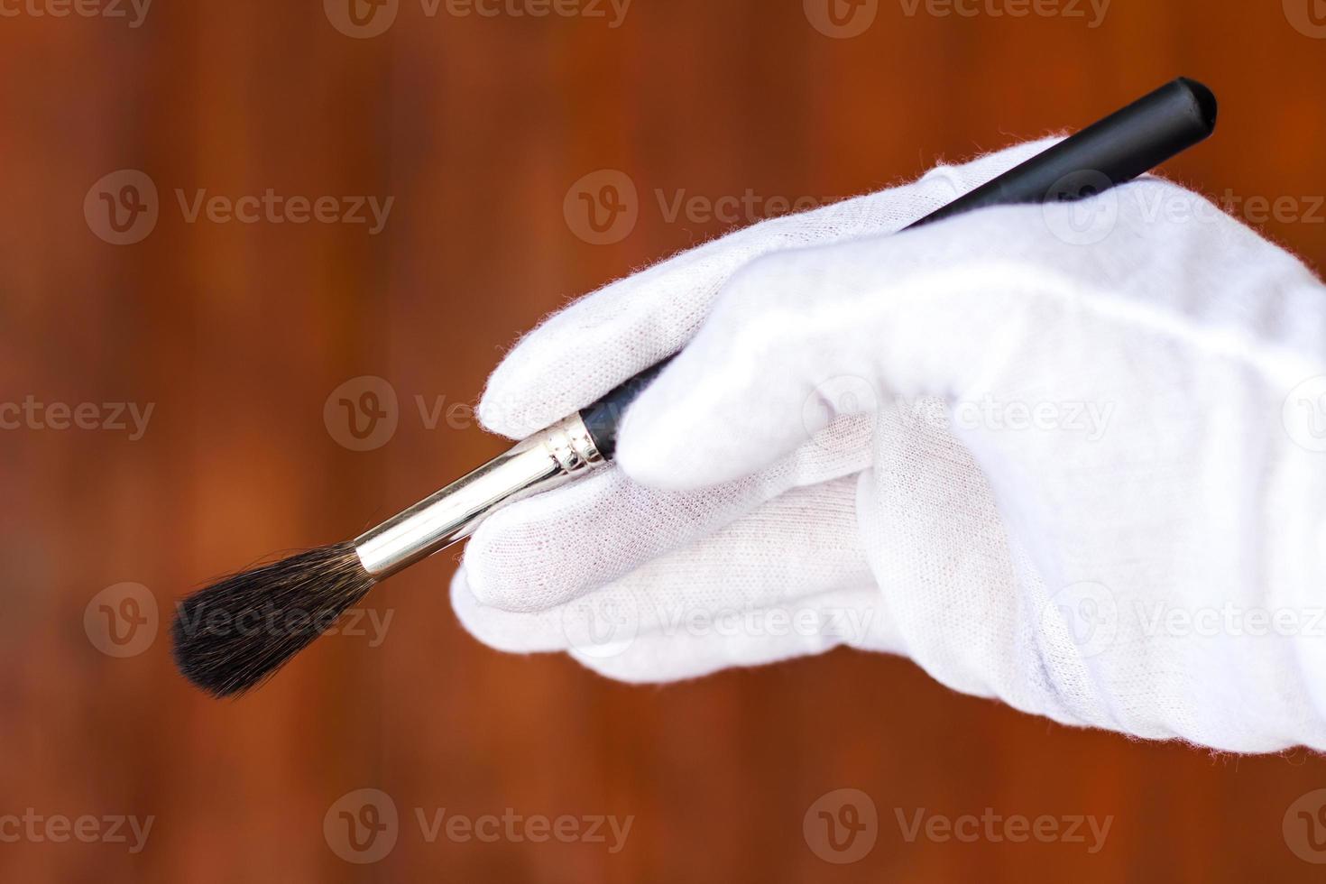 White gloved hand holding a paintbrush. photo