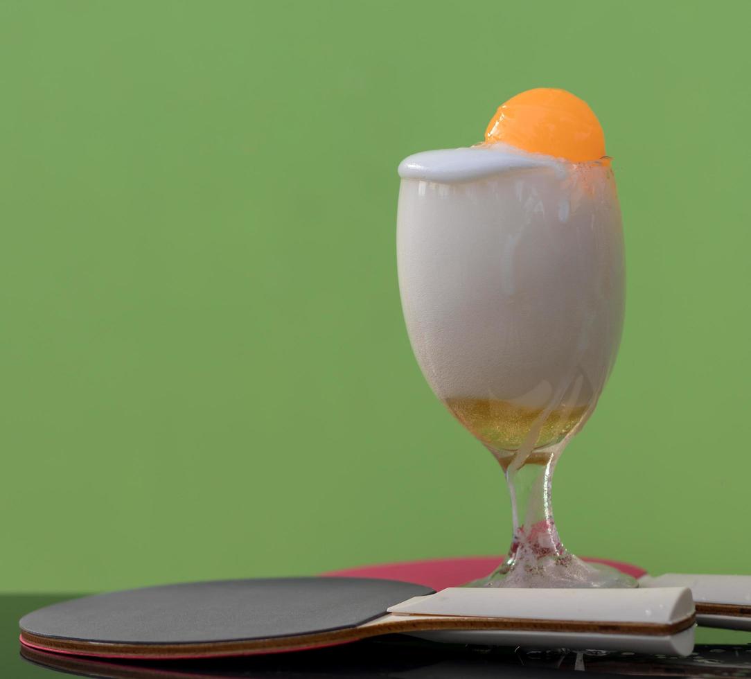 Bubbles of beer in a glass with a ping pong ball. photo