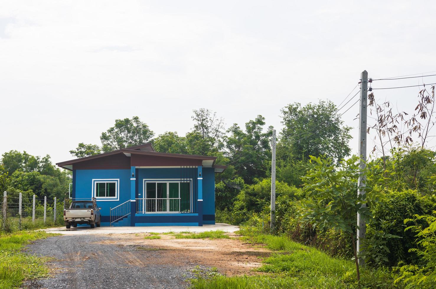 una sola casa azul con un auto entre los árboles. foto