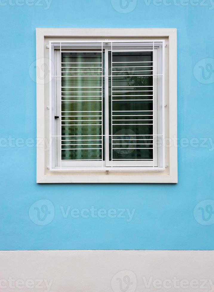 Close-up view, background of white concrete window frames with wrought-iron grilles. photo