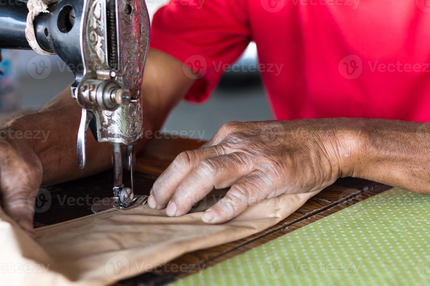 Elderly hand with a sewing machine. photo