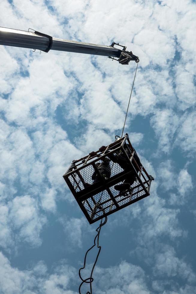 Low silhouettes of workers in steel baskets with sky clouds. photo