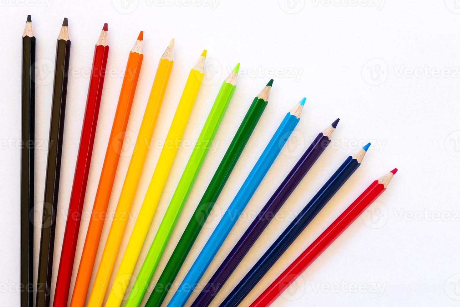 Many colorful pencil isolates spread on white paper. photo