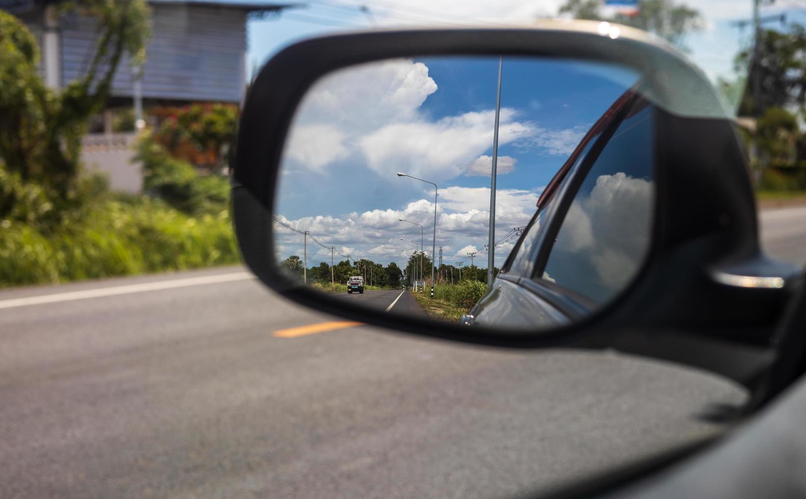 Sky clouds from the side mirrors of the car during daytime in the countryside. photo