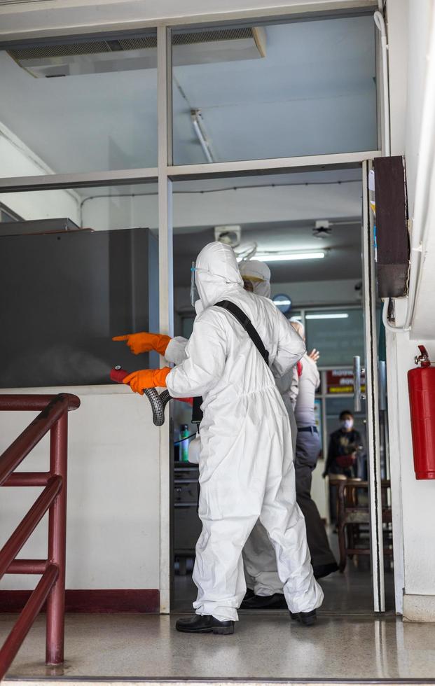 Both of them, wearing PPE uniforms, were sprayed to clean the glass room. photo