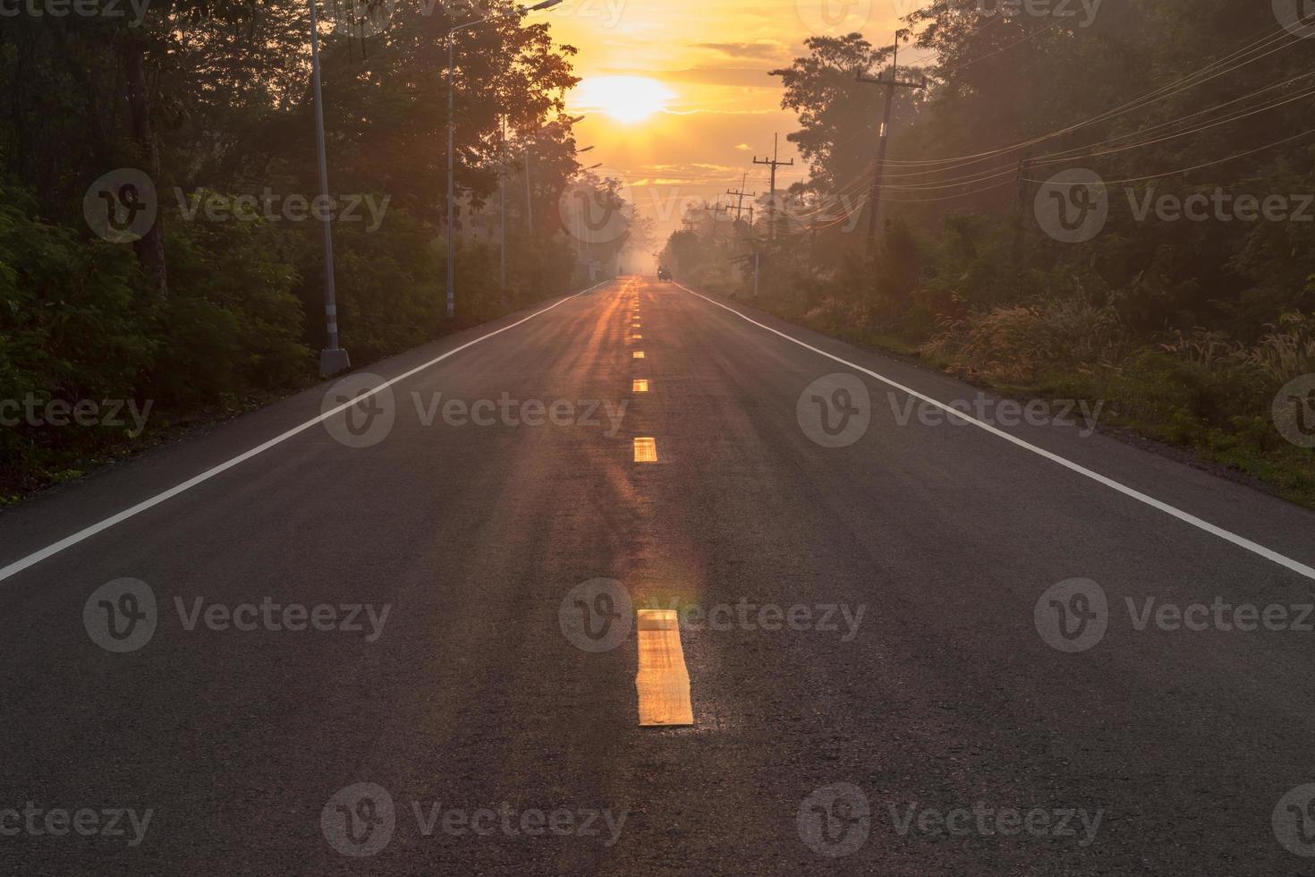 carretera asfaltada con sol naciente en el campo. foto