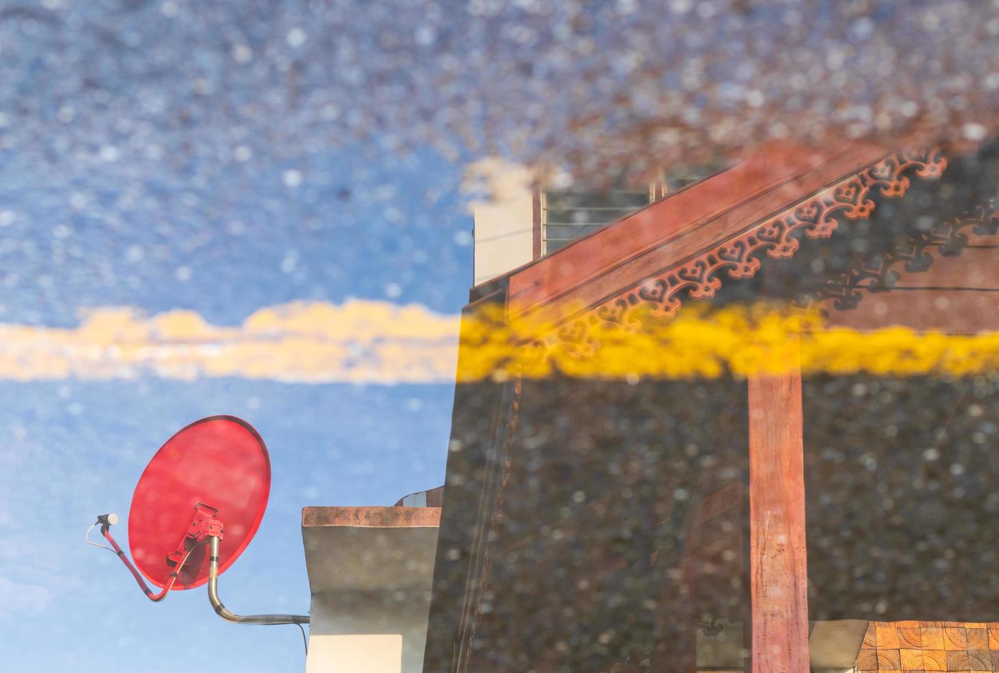 The water reflection of the red satellite dish against the building. photo