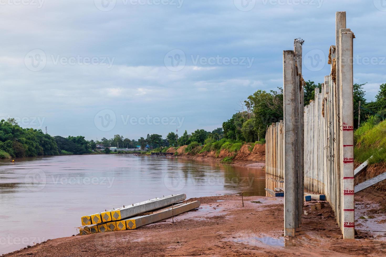 Many views of concrete columns near the river shore. photo