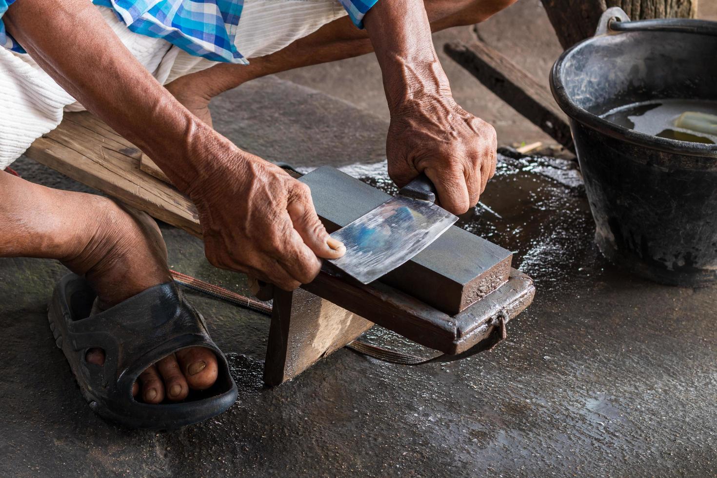 The hand sharpens knives and the whetstone on the bench. photo