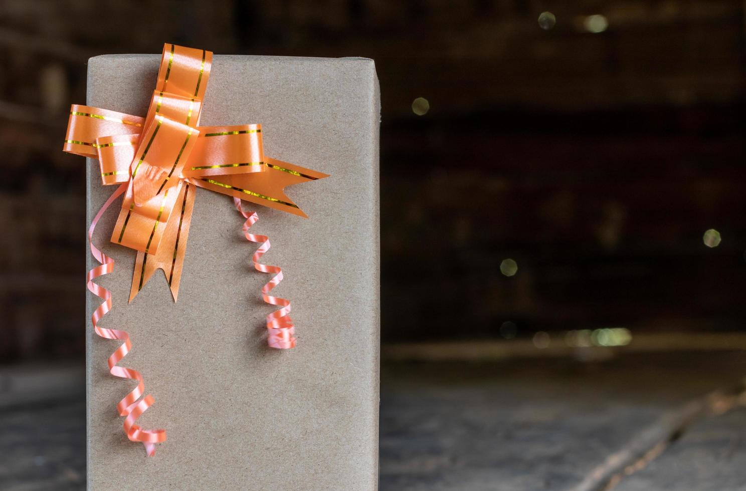 caja de papel de regalo con lazo naranja en una antigua sala de madera. foto