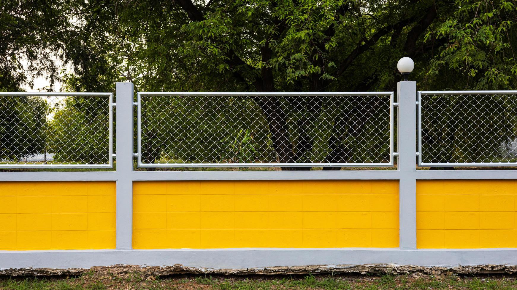 Yellow concrete wall fence with forest garden. photo