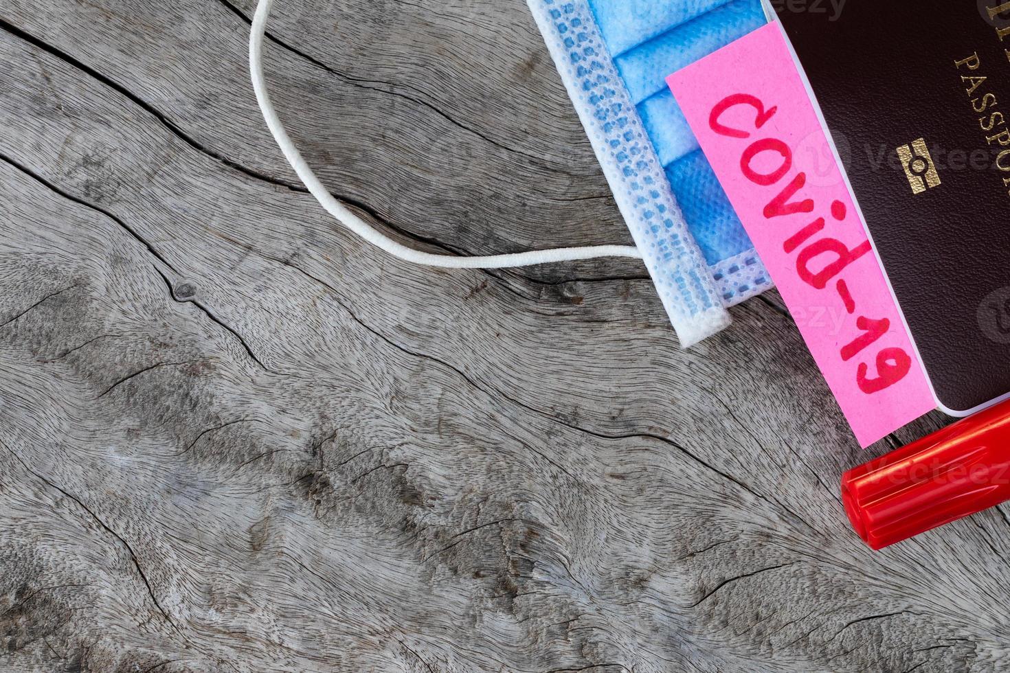 COVID-19 with passport and face mask on wooden floor. photo