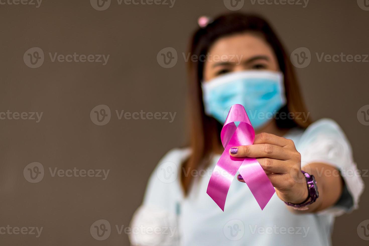 Close-hand woman wears a mask as a symbol against breast cancer. photo