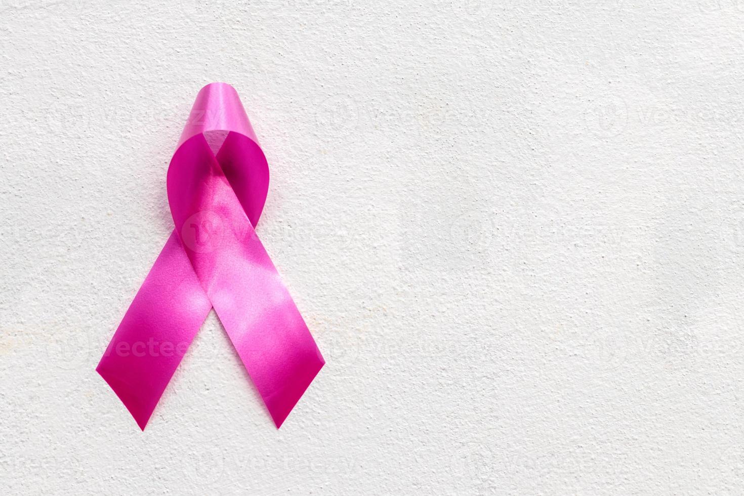 arco símbolo de cinta rosa para el cáncer de mama contra la pared de hormigón. foto