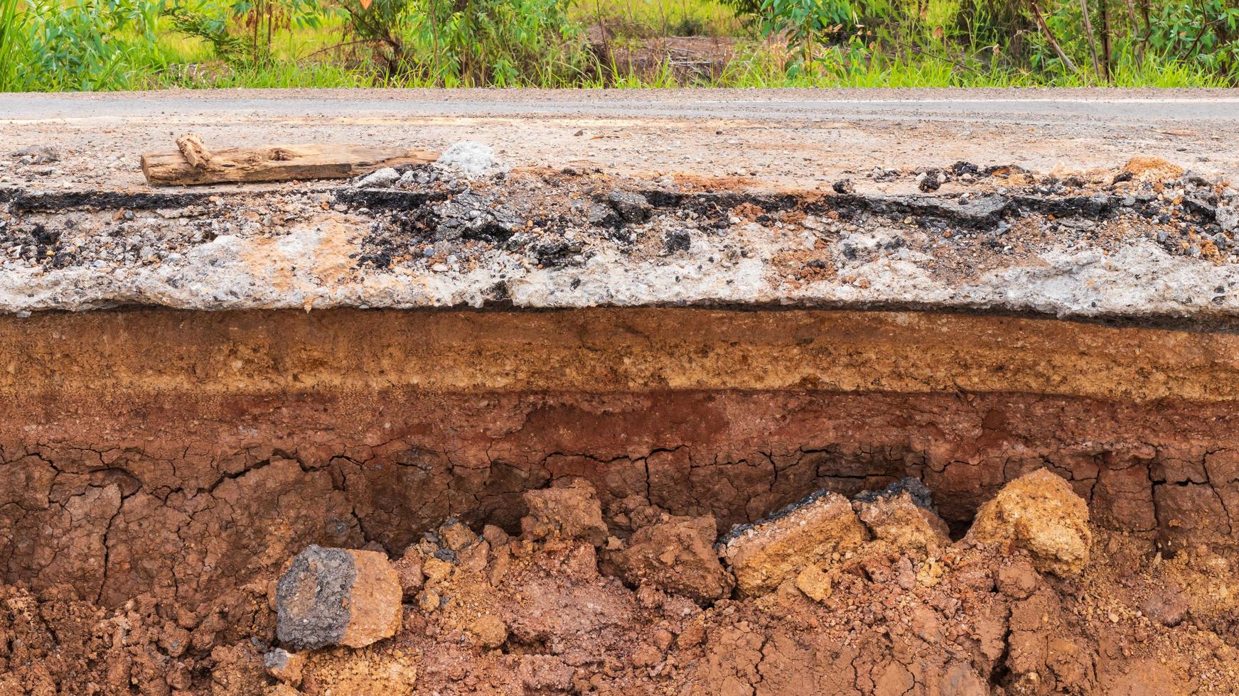 la capa de suelo ha sido erosionada bajo el camino rural pavimentado. foto