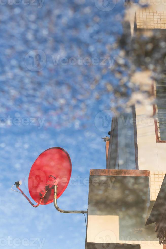 el reflejo del agua de la antena parabólica roja contra el edificio. foto