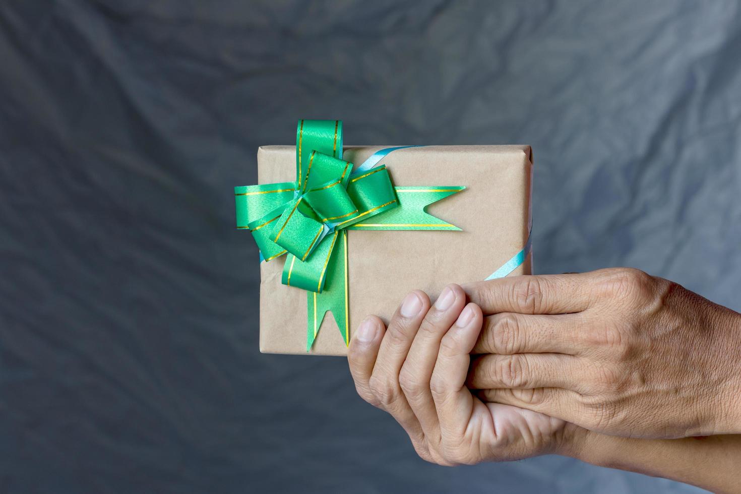 mano sujetando la caja de regalo y el lienzo de pajarita como telón de fondo. foto