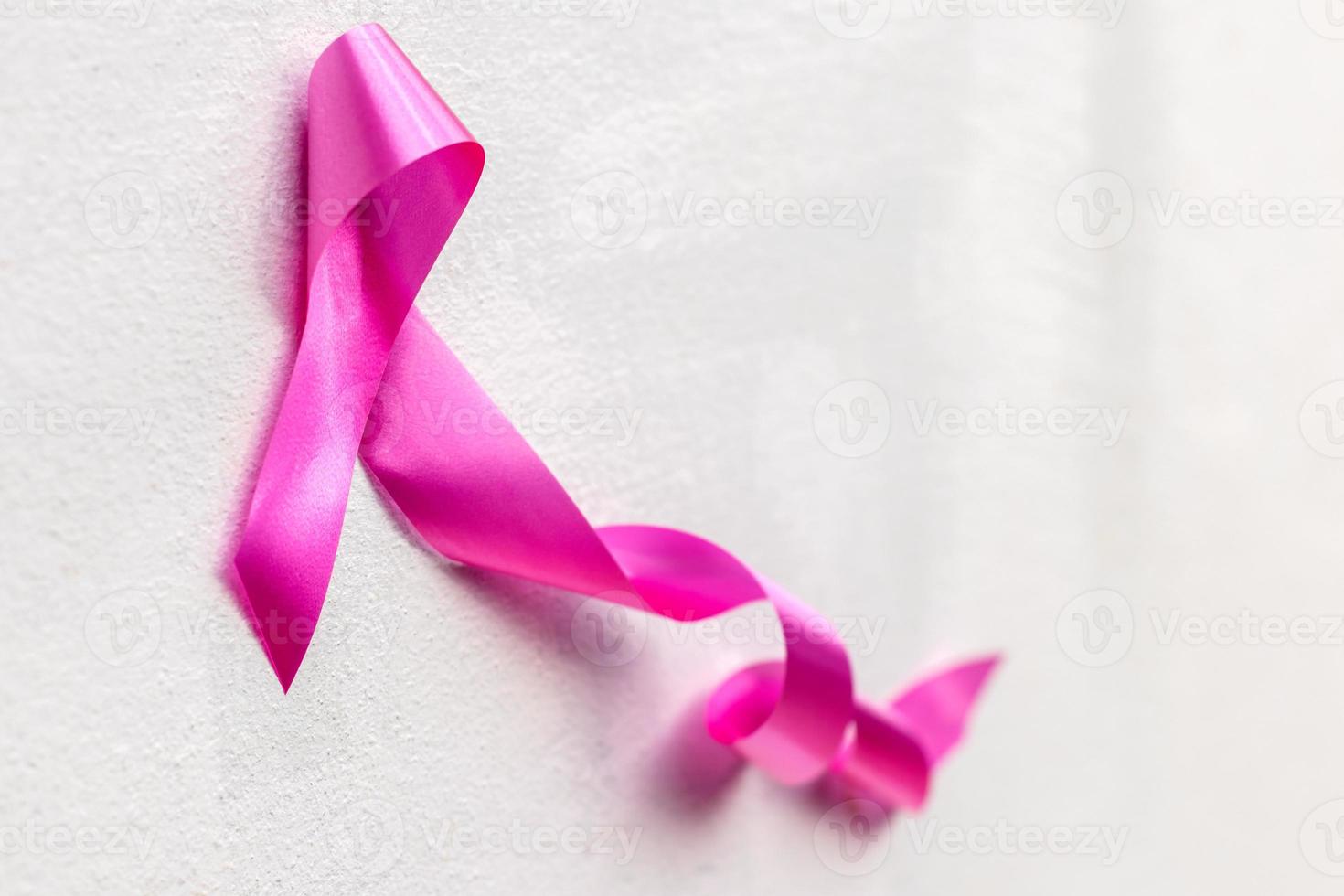 arco símbolo de cinta rosa para el cáncer de mama contra la pared de hormigón. foto