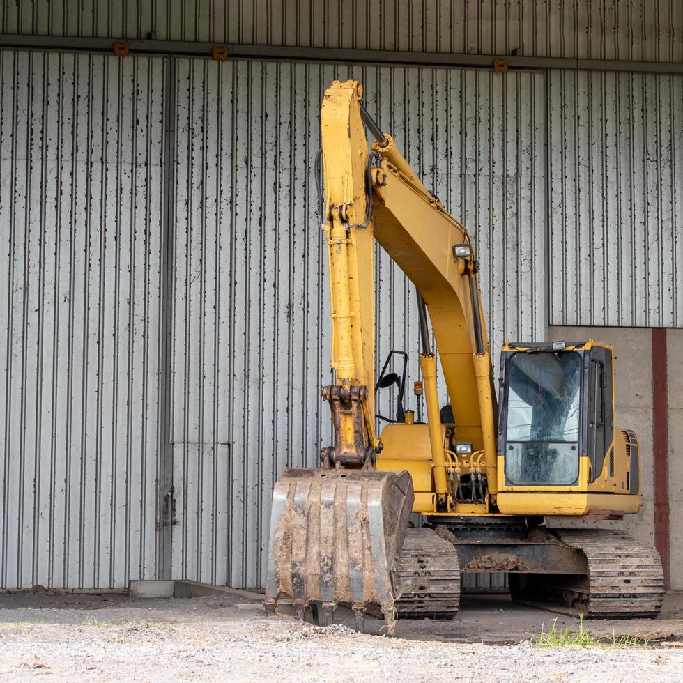 Yellow backhoe near the zinc wall. photo