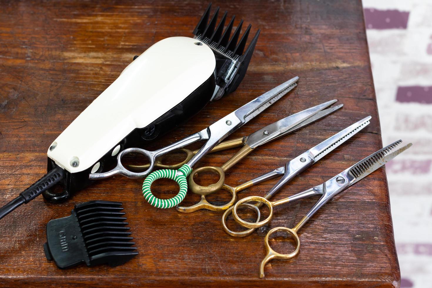 Clippers and many scissors placed on the wooden table. photo