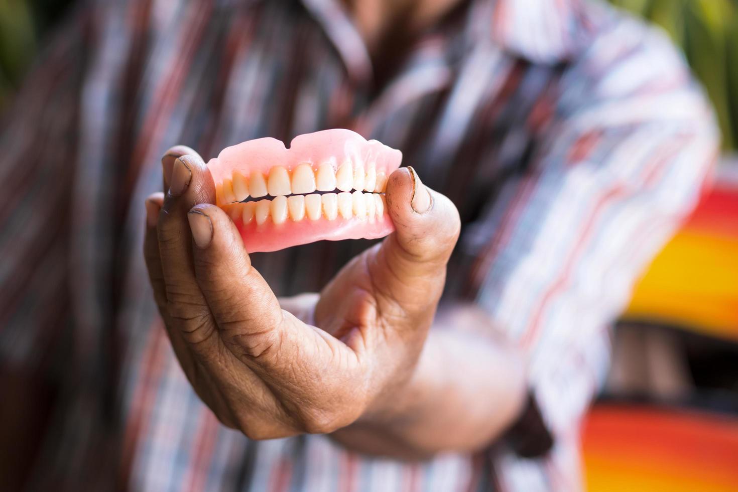 Dentures in the hands of elderly men in rural Thailand. photo