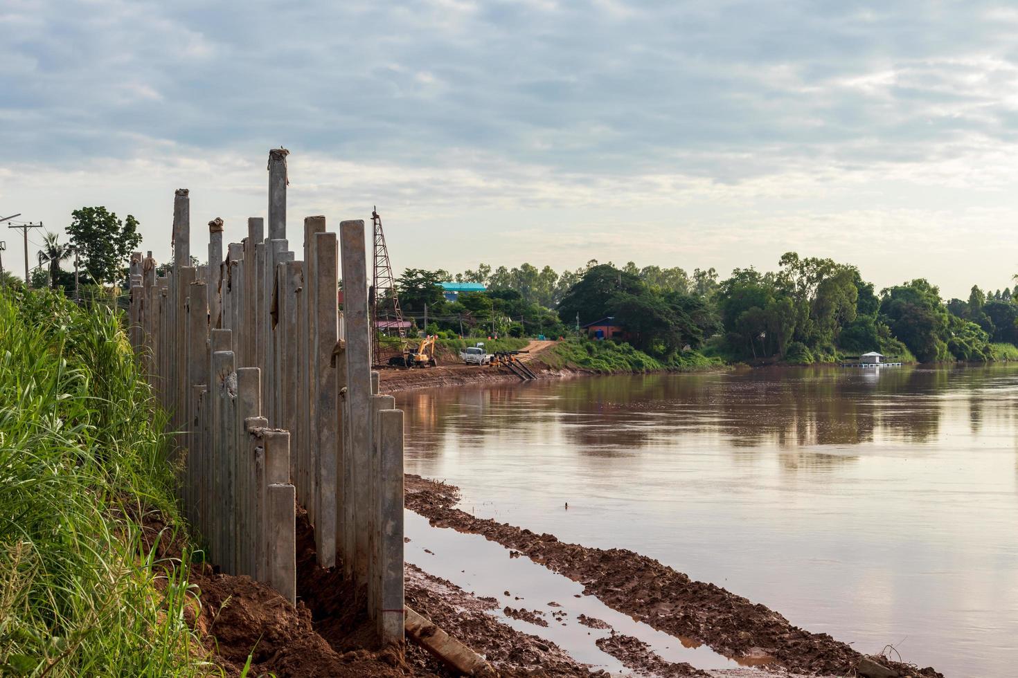 muchas columnas de hormigón forman un largo muro cerca de la orilla del río. foto