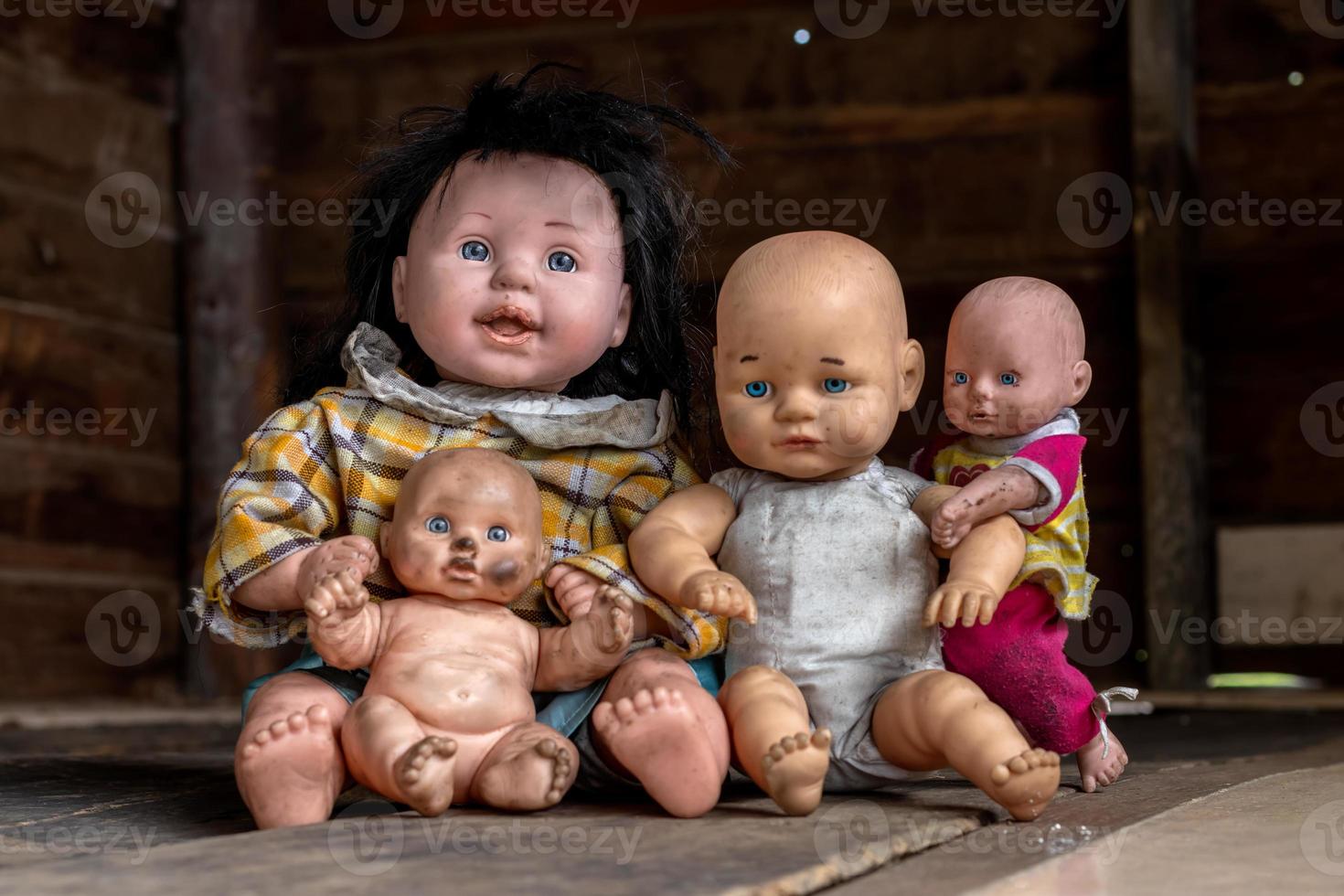 un grupo de muñecas sentadas en una vieja casa de madera. foto