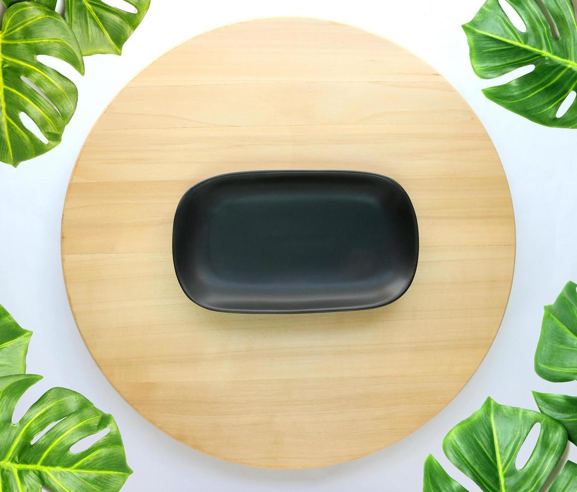 dish is placed on a round wooden table with monstera palm leaves for decoration photo