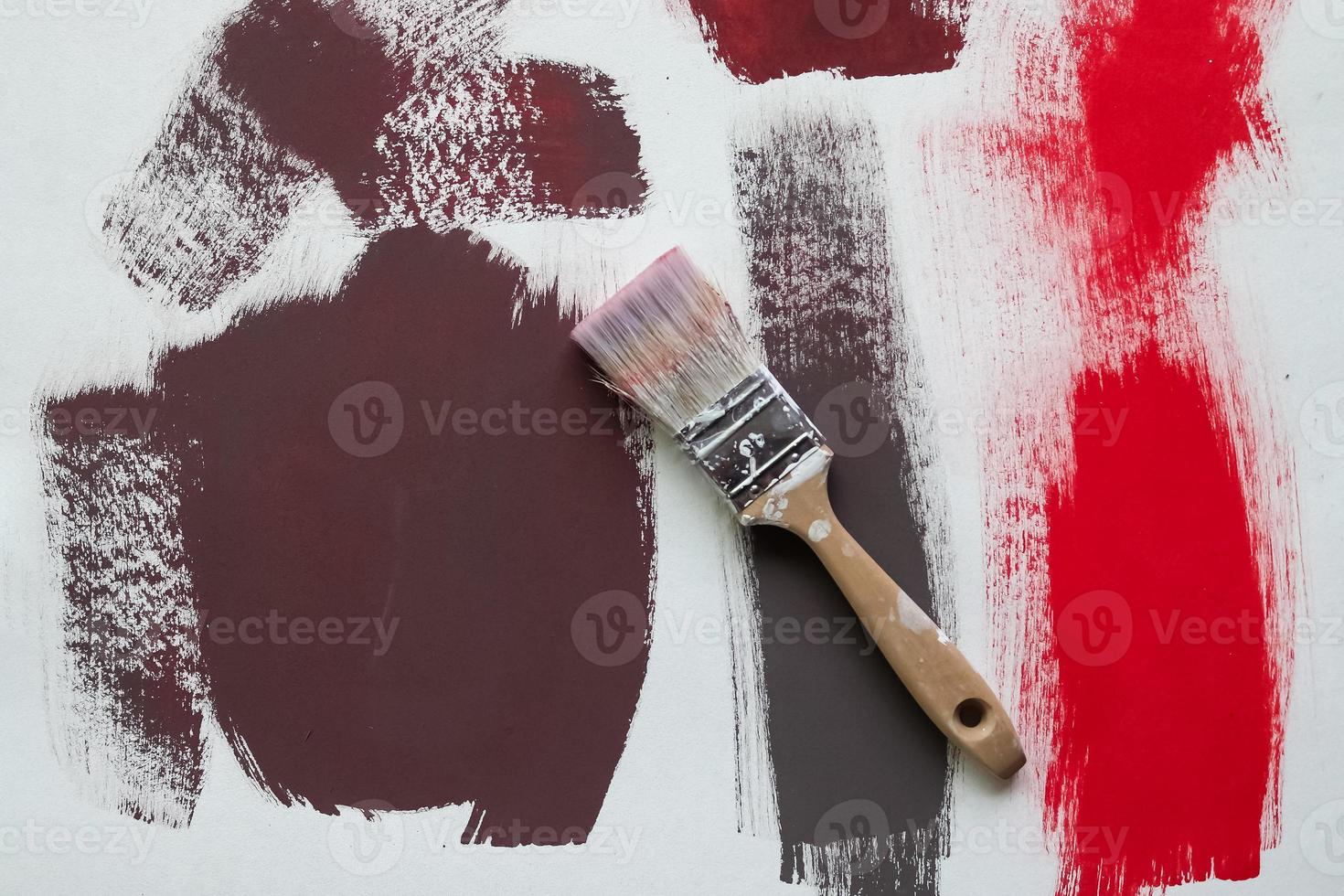 Concept of a paintbrush on a piece of paper with brush strokes in red and brown photo