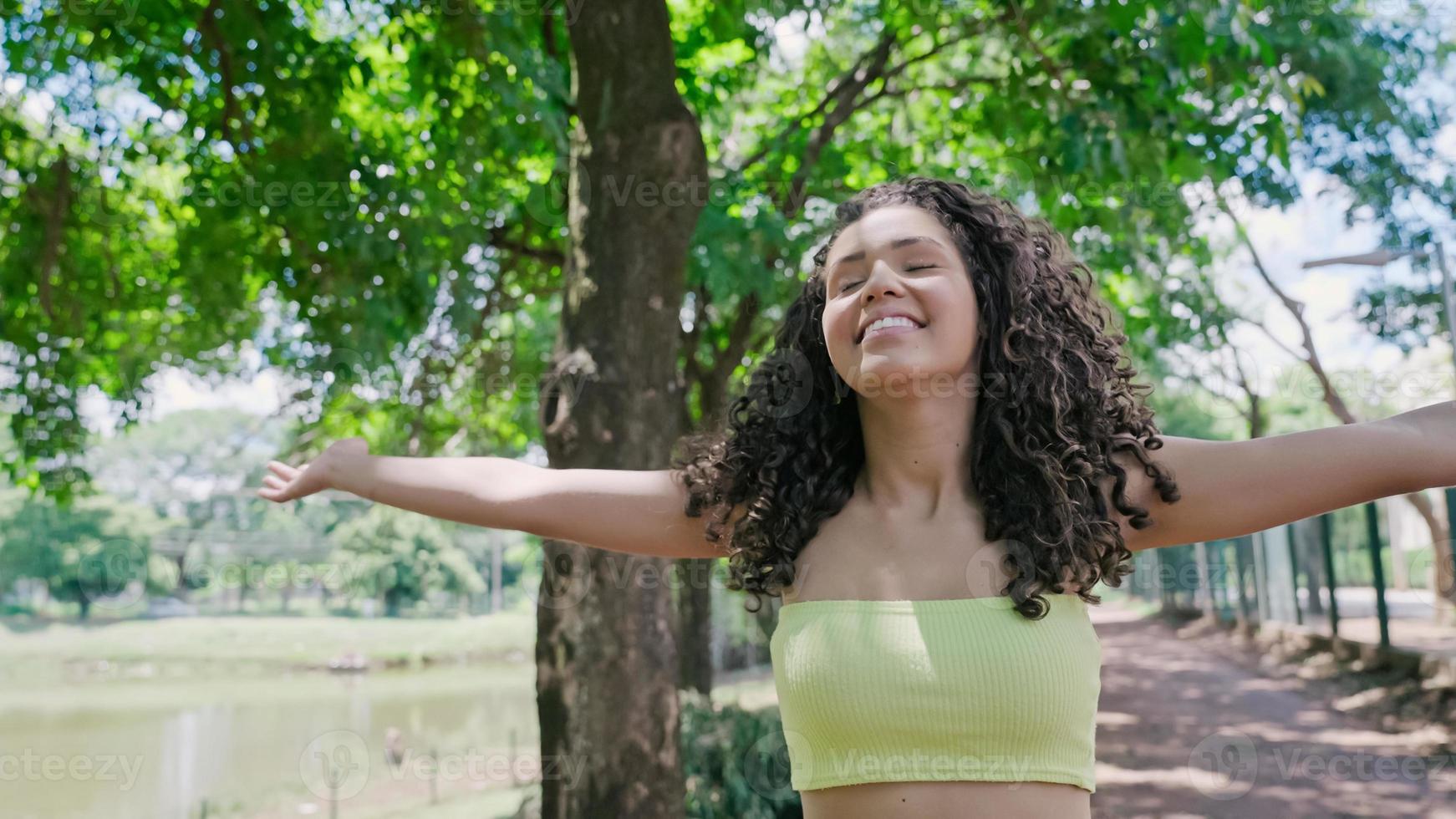 atractiva mujer latina caminando en el parque en un día soleado y sonriendo. foto