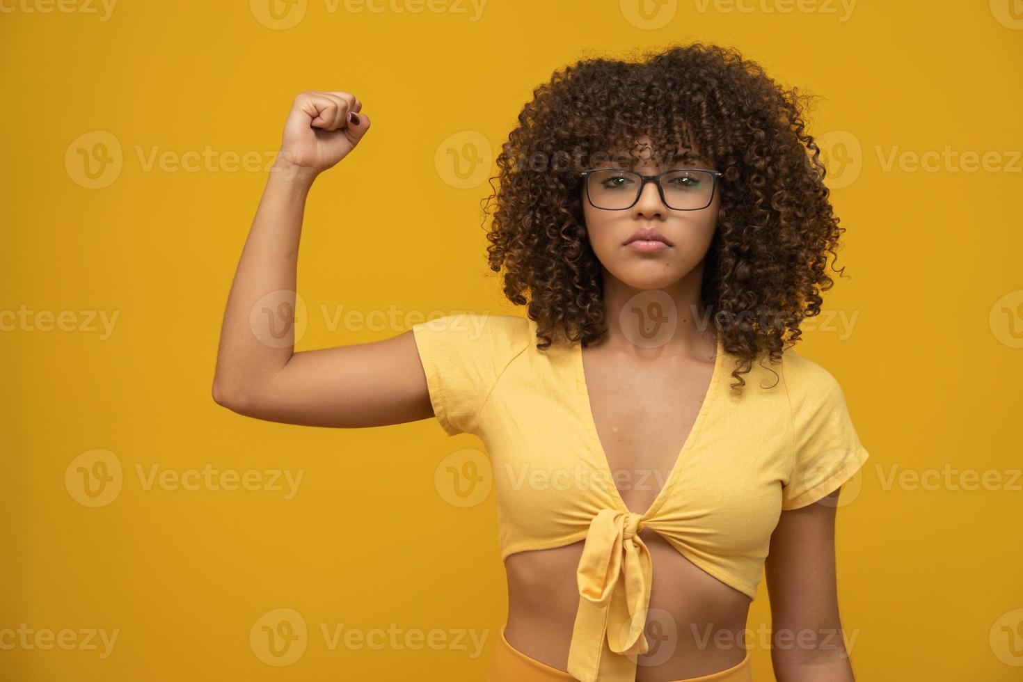 We can do it. Woman's fist of female power. Woman victim of racism. Abuse at work. The feminine power. Female empowerment. The strength of women. Yellow background. photo