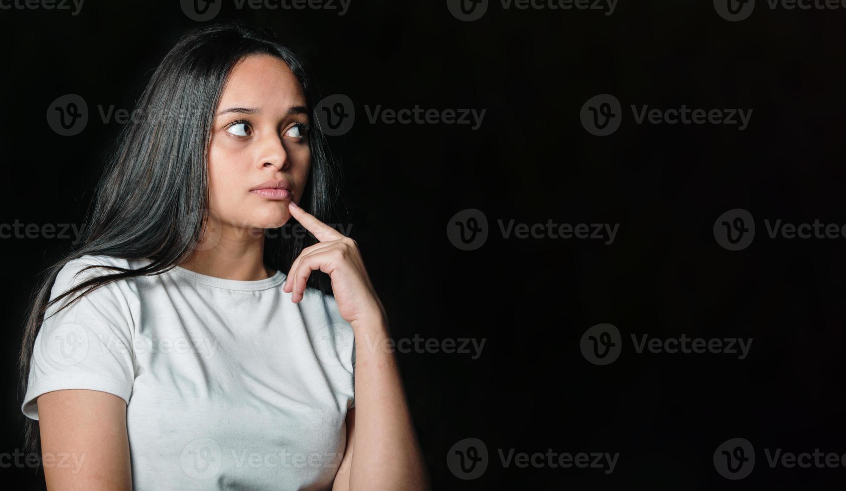 Young beautiful teen student girl dreaming thinking looking in side over dark background. photo