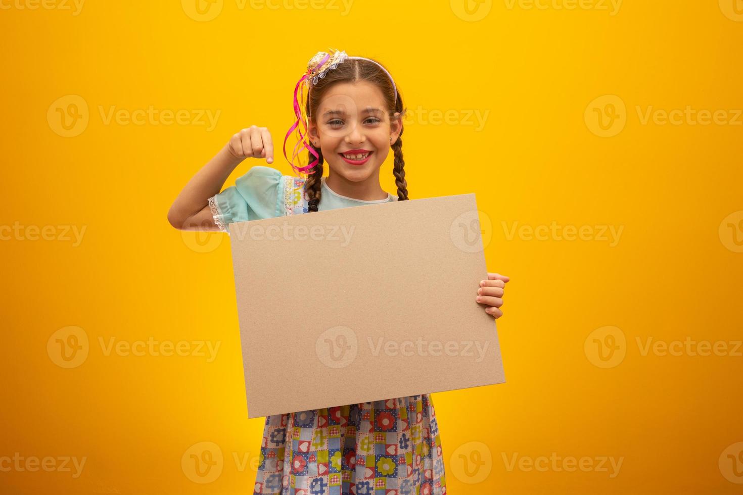 Child in typical clothes of famous Brazilian party called Festa Junina in celebration of Sao Joao. Beautiful girl on yellow background. photo