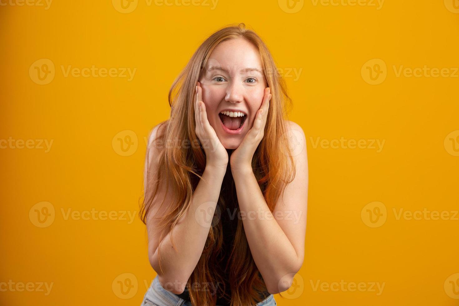 Overwhelmed excited smiling, happy redhead girl celebrating amazing news, achieve victory, winning competition, triumphing as become champion, gain goal or unexpected lucky event happened. On yellow. photo