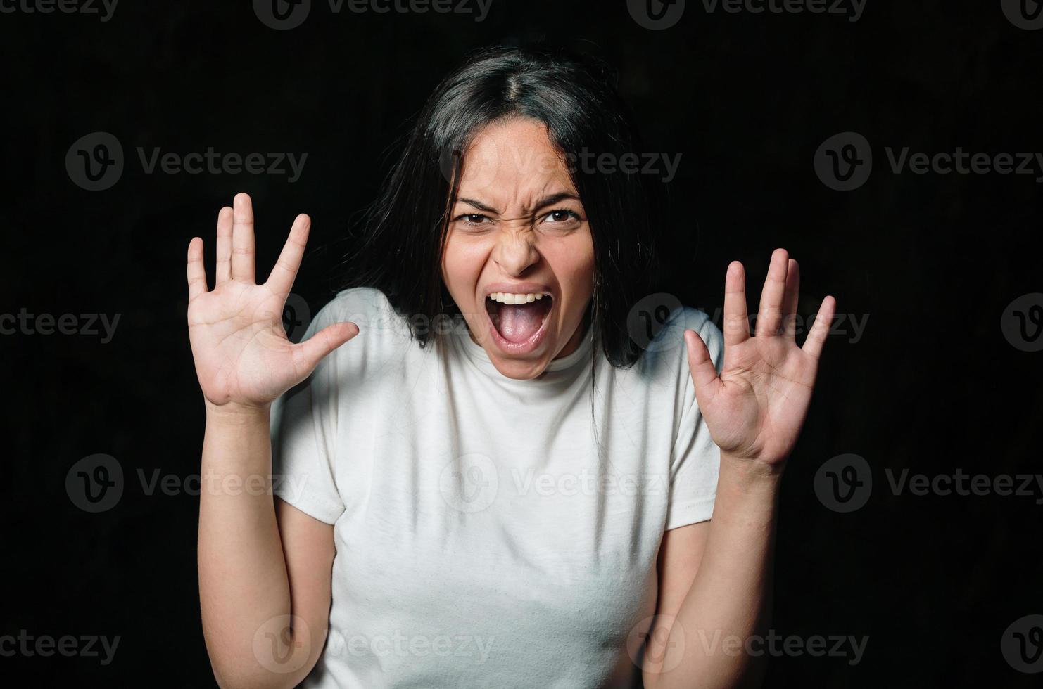 Teen woman screaming wild and crazy at full energy looking at camera in outdoor. Beautiful mixed race caucasian brunette girl model. photo