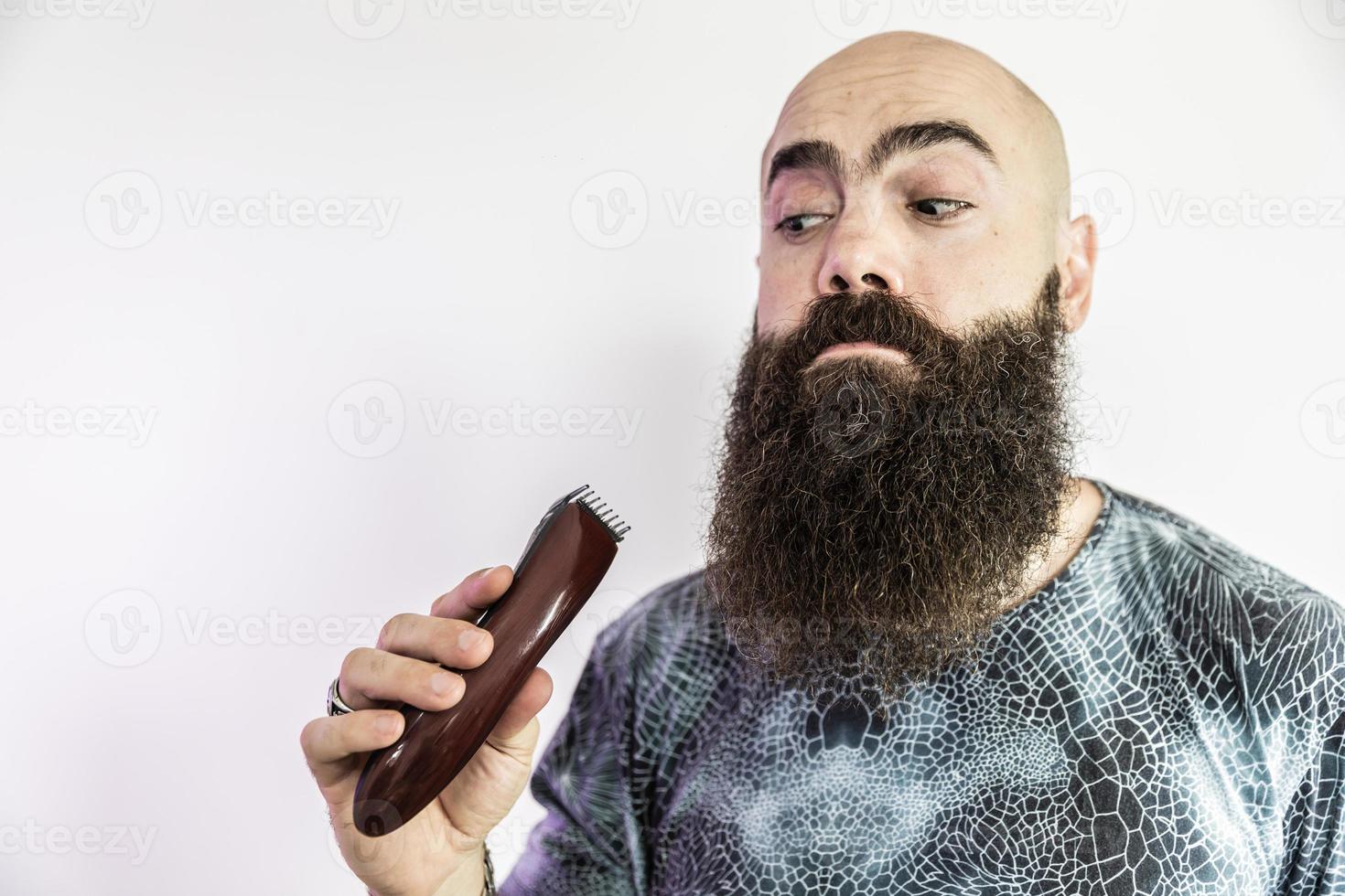el hombre barbudo se afeitará la barba con una afeitadora electrónica foto