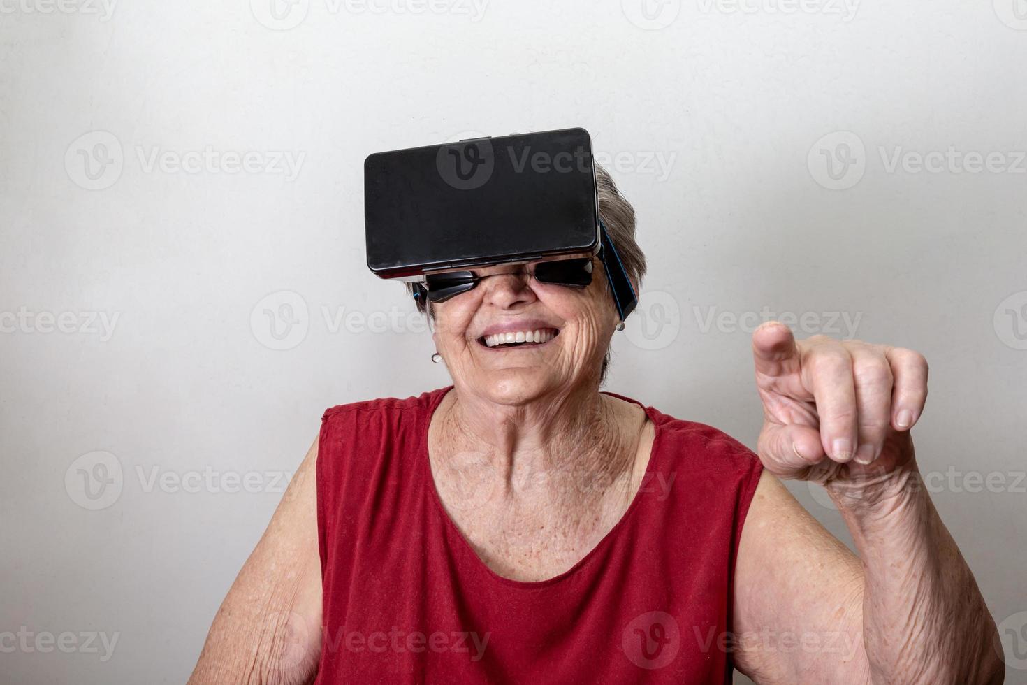 Happy grandmother use modern VR goggle glass on white background. New trends and technology concept and funny active elderly. photo