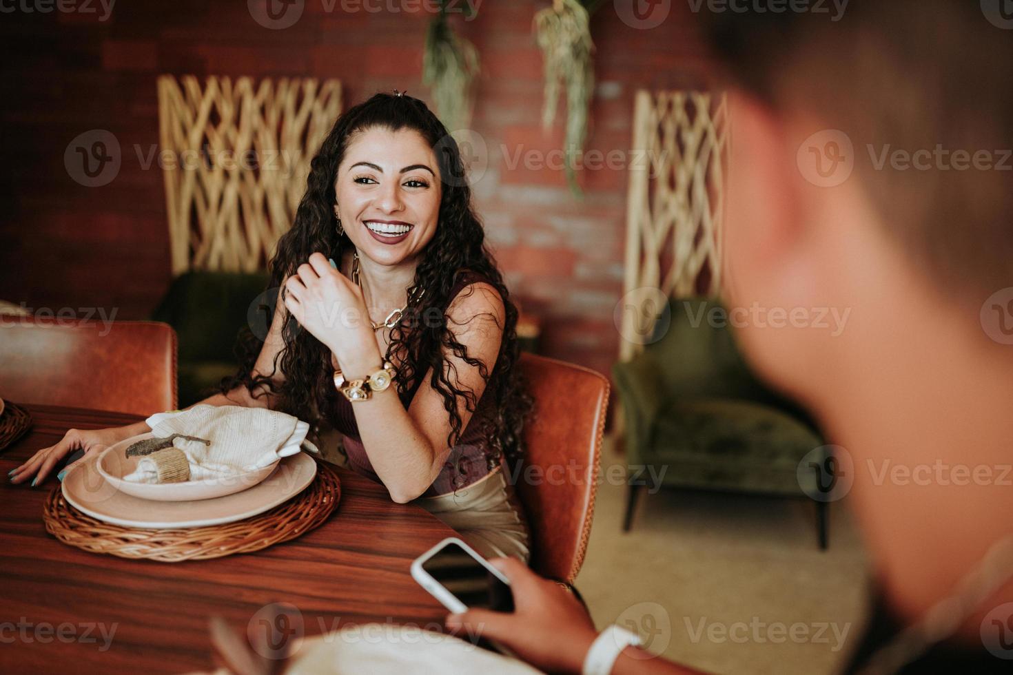 Two Latino friends gathering around a table in a restaurant or at home photo