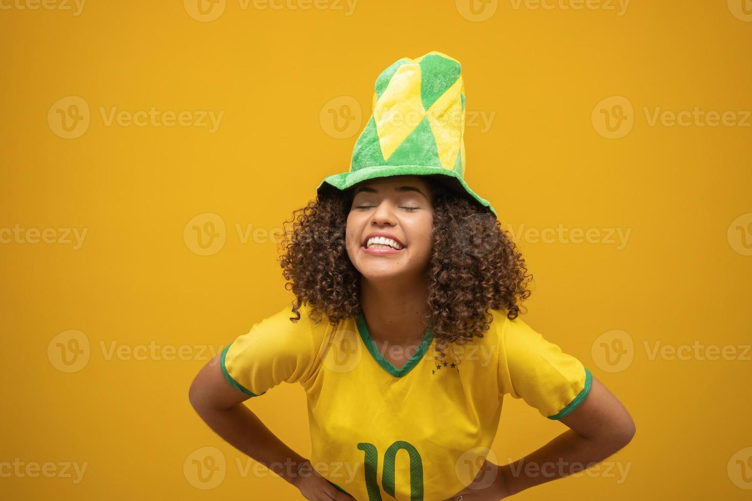 partidario de brasil. hincha brasileña celebrando un partido de fútbol con fondo amarillo. colores de brasil. foto