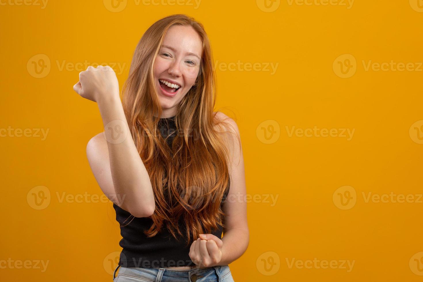 abrumada, emocionada, sonriente, feliz pelirroja celebrando noticias increíbles, logrando la victoria, ganando la competencia, triunfando como campeona, ganando el gol o sucedió un evento afortunado inesperado. en amarillo foto