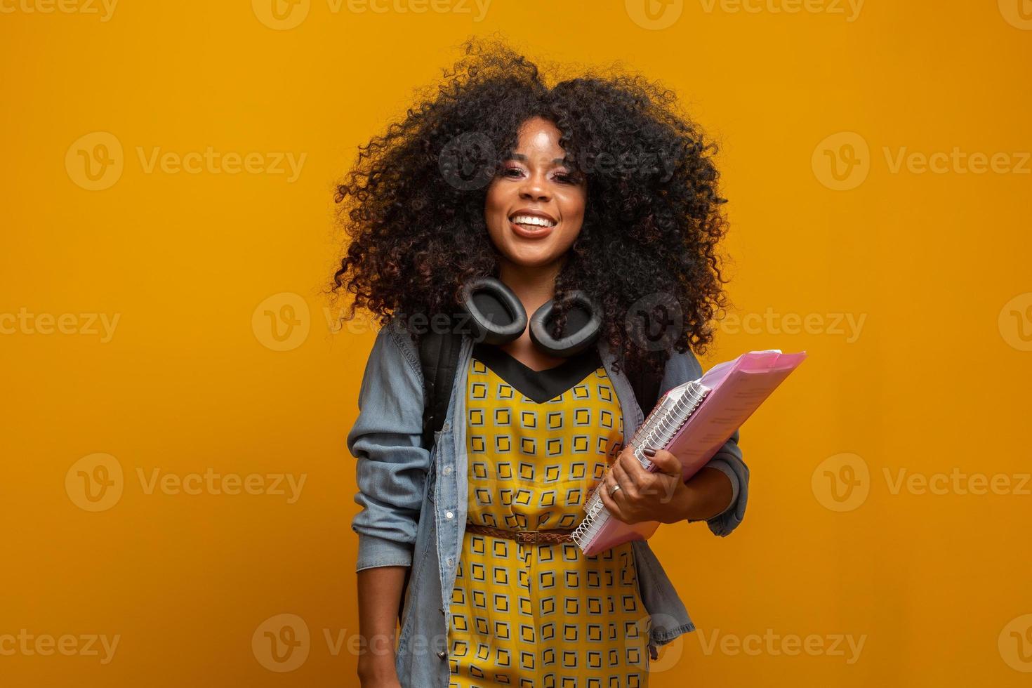 Female student in campus with books in her arms. Yellow background. photo