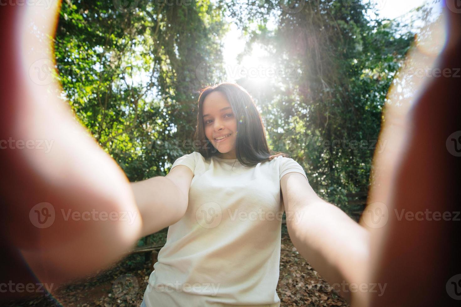 Portrait of a smiling young girl making selfie photo in park
