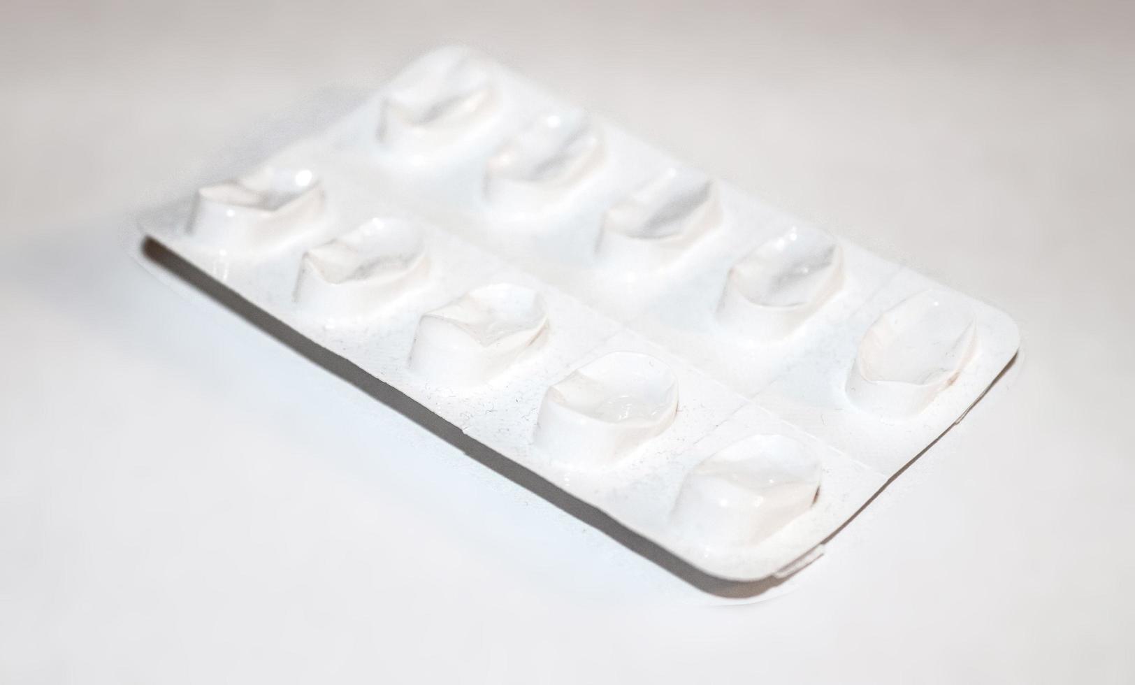 Pharmacy drugstore concept. Packs of white pills packed in blisters with copy space isolated on a white background. Focus on foreground, soft bokeh. photo